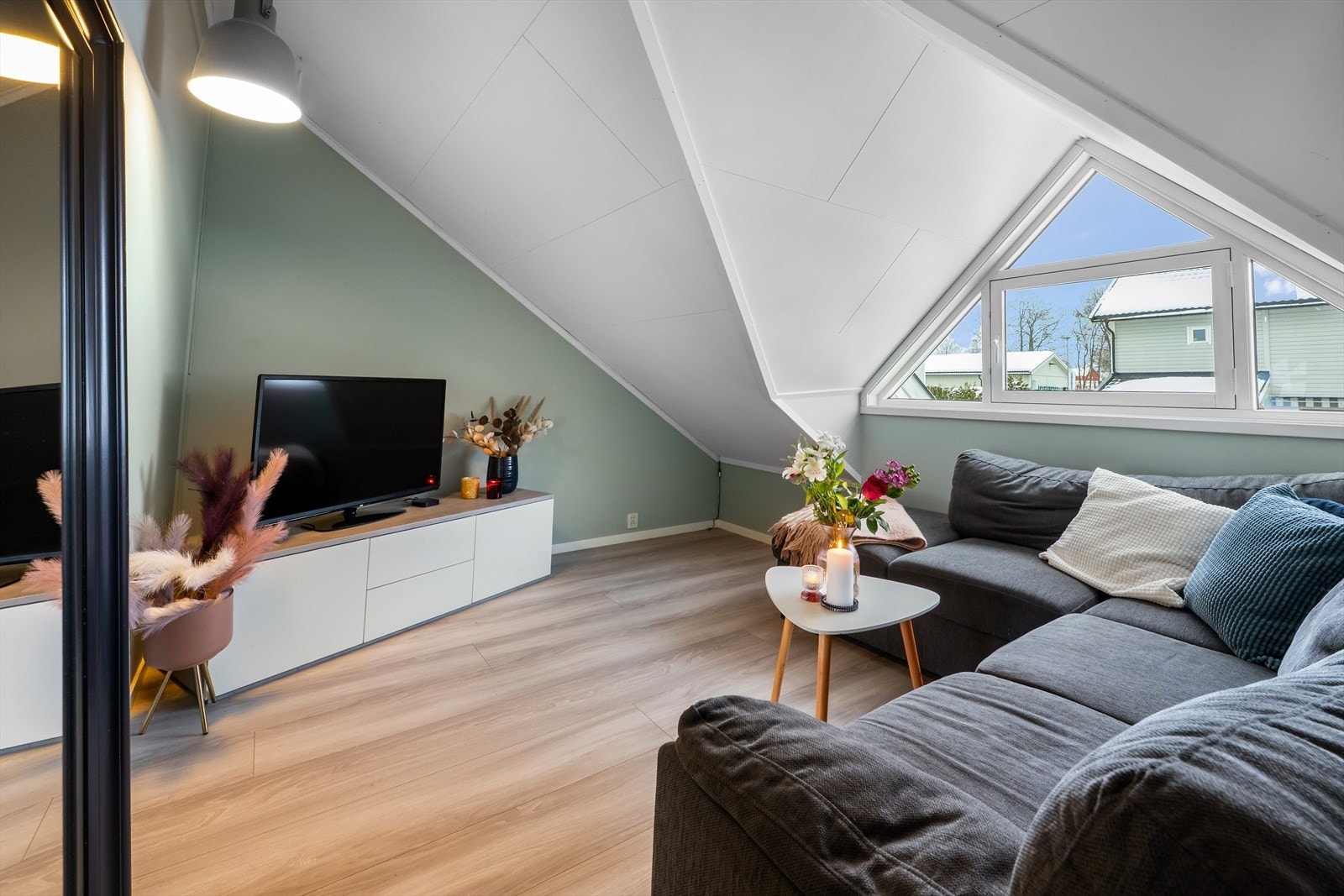 Loftsstue med skråtak har stort vindu som gir rikelig med dagslys. Galleribilde