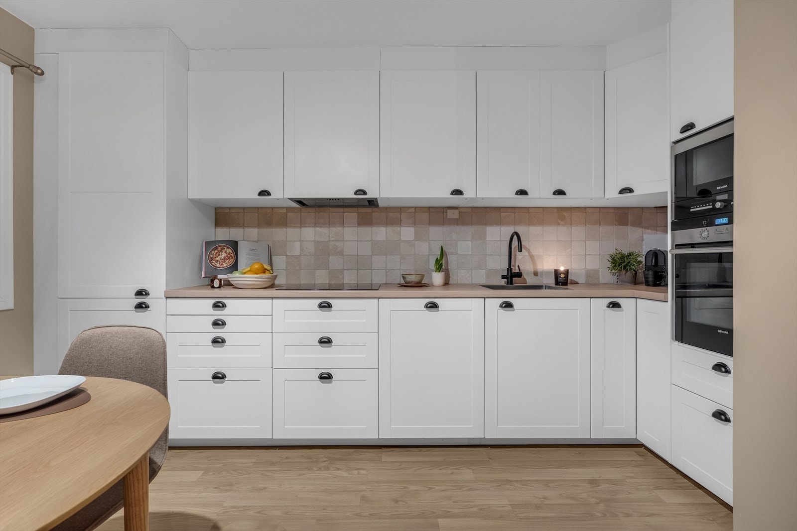 Hvite profilerte fronter og laminert benkeplate gir et stilrent uttrykk. Galleribilde