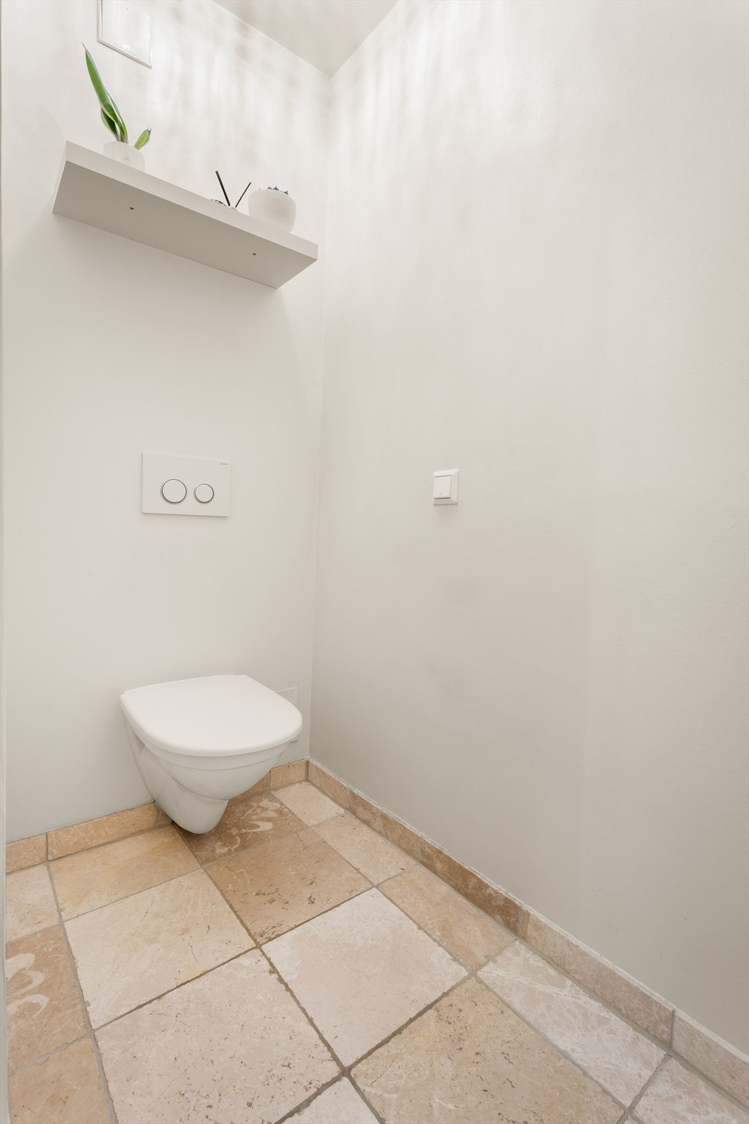 Vegghengt toalett med flislagt gulv gir et rent og funksjonelt uttrykk. Galleribilde