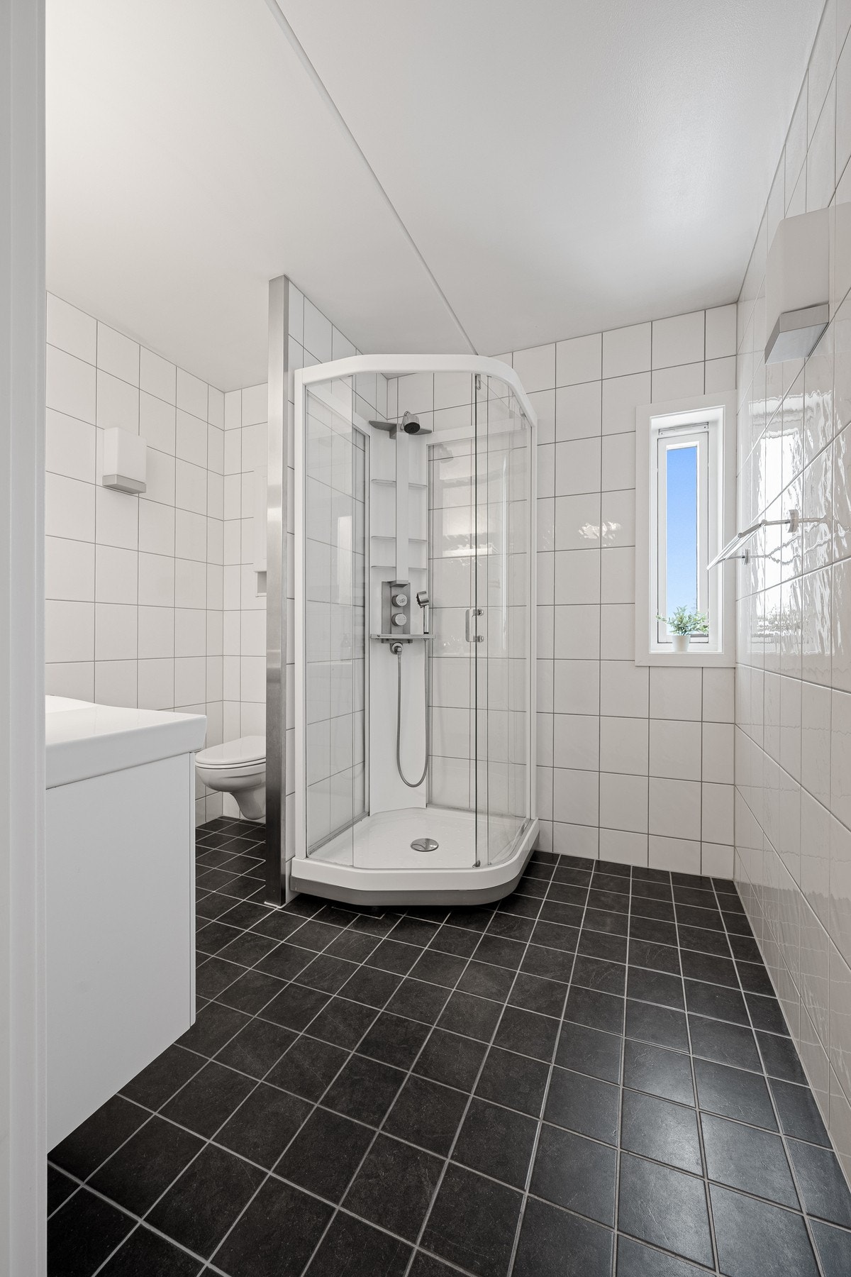 Rommet fremstår som funksjonelt med flislagt gulv med behagelige varmekabler, flislagte vegger og malte plater i himlingen. Galleribilde