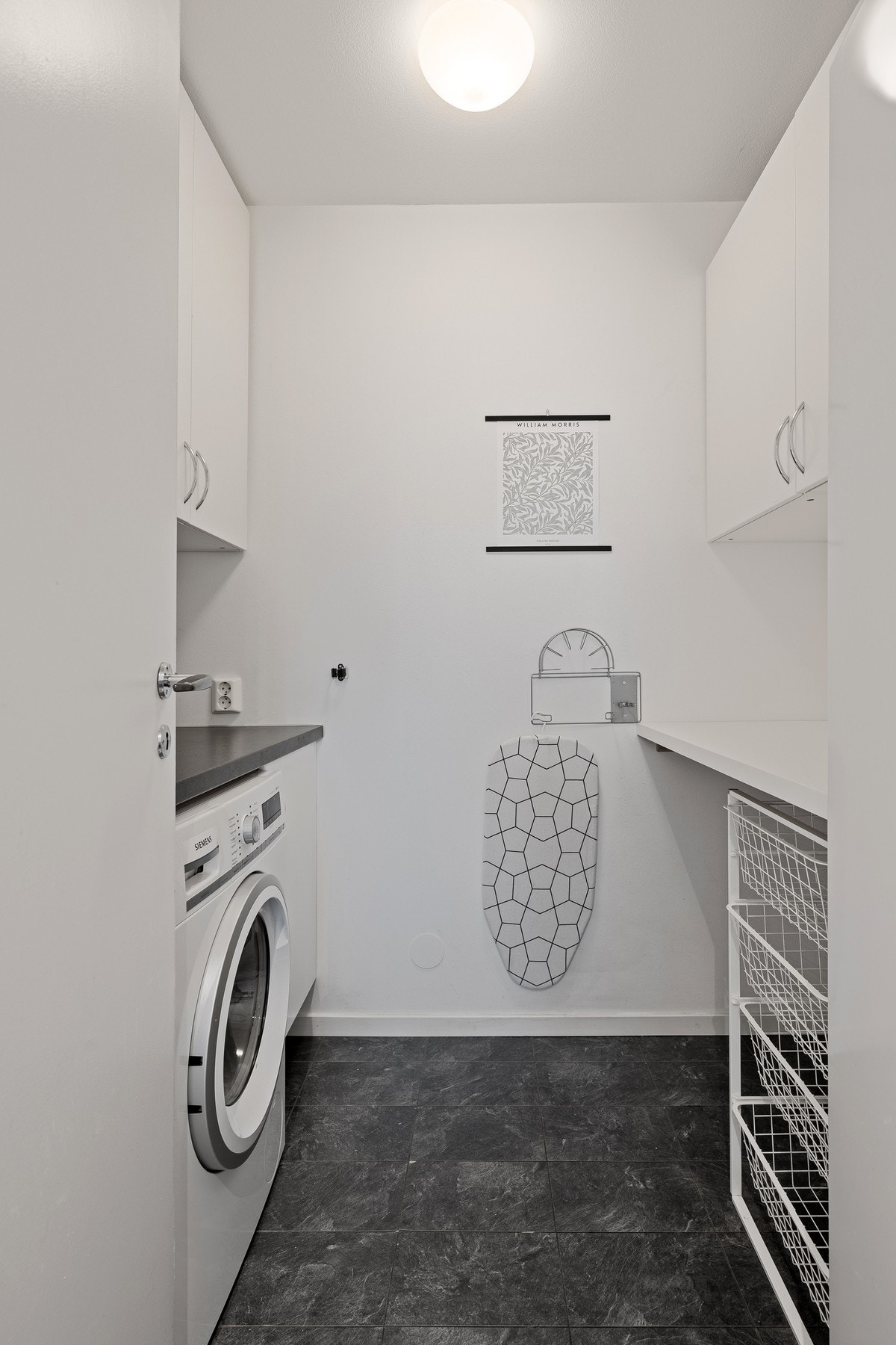 Leiligheten har en praktisk kombinert bod og vaskerom med plass til vaskemaskin, med adkomst direkte fra kjøkkenet. Galleribilde