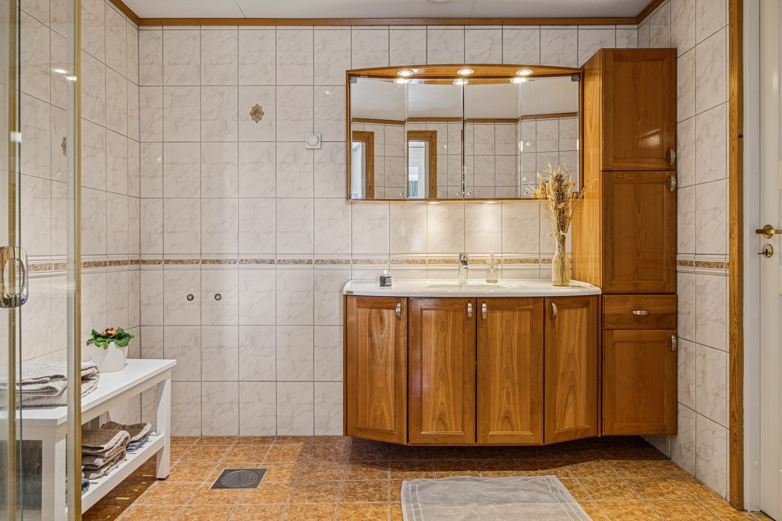 Baderomsinnredning med servantskap, heldekkende servant og speilskap med belysning. Galleribilde