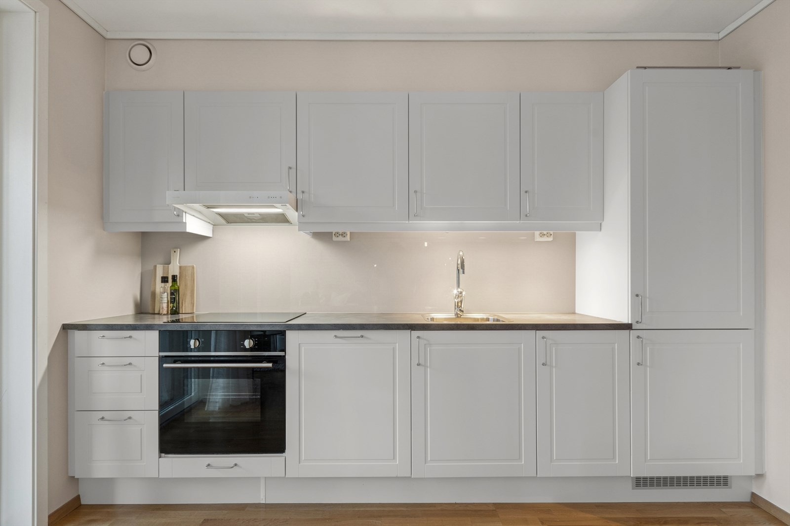 Kjøkkenet har profilerte fronter og er godt utbygget med skap- og benkeplass. Over benkeplaten er det montert en glassplate og det er en nedfelt stålvask. Galleribilde