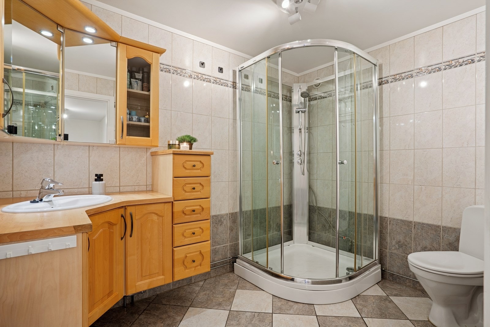 Badet er utstyrt med innholdsrik innredning, dusjkabinett og wc. Flislagte gulv og vegger. Gulvvarme Galleribilde