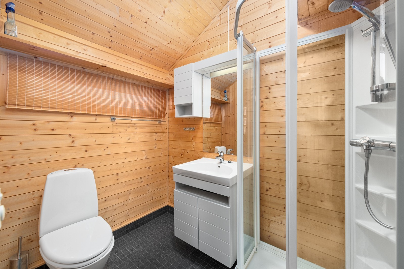 Badet i annekset har flislagt gulv med gulvvarme og er utstyrt med servantinnredning, toalett og dusjkabinett. Galleribilde