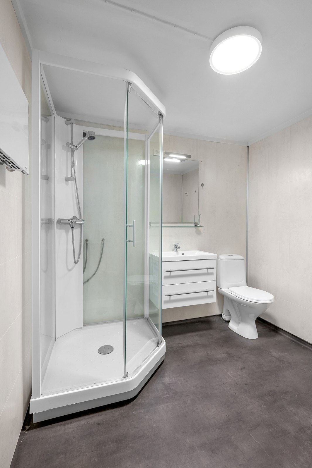 Bad utstyrt med dusjkabinett, servant med underskap og toalett Galleribilde