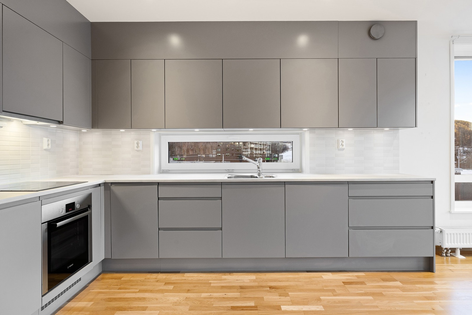 Parkett på gulv og flis på vegg over benkeplate på vegger. Galleribilde