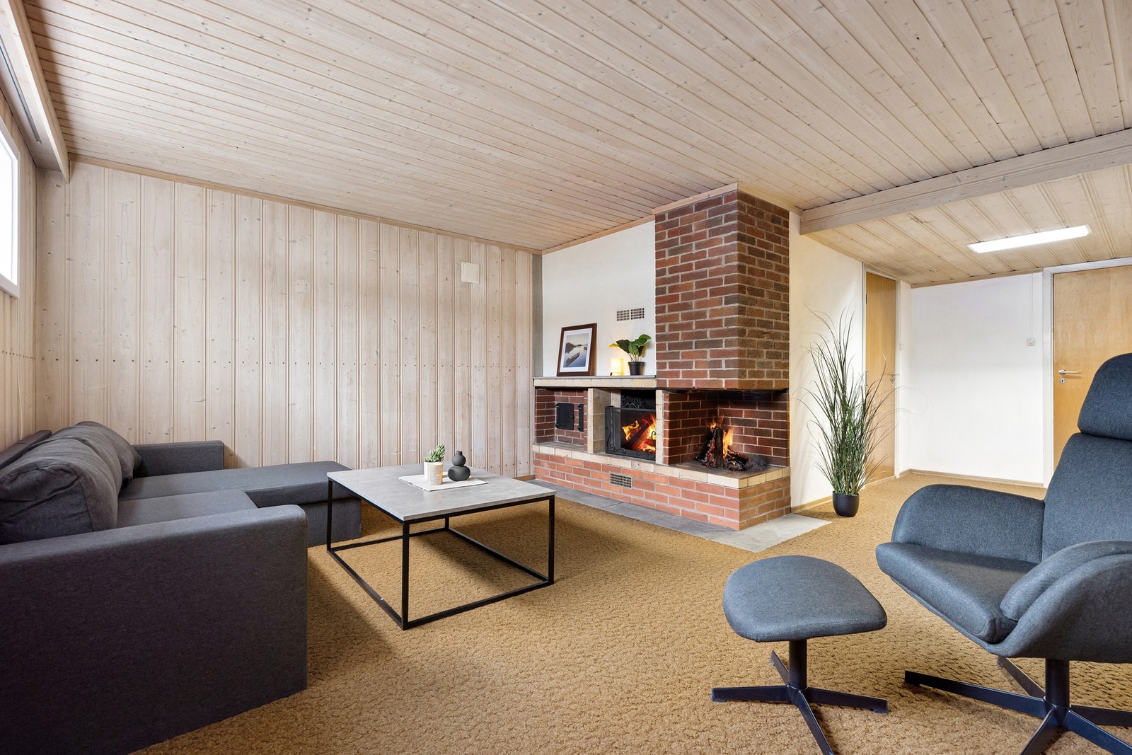 Kjellerstue med mange bruks- og møbleringsmuligheter med en koselig peis. Galleribilde