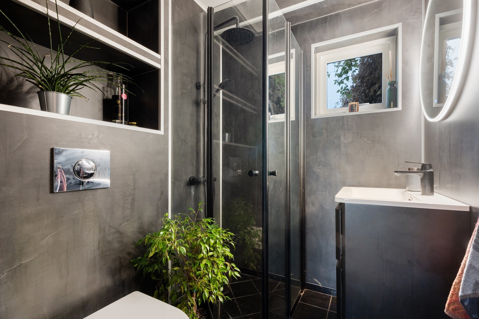 Stilig bad i 1. etasje med flislagt gulv med varmekabler, baderomsplater og vegghengt toalett. Galleribilde