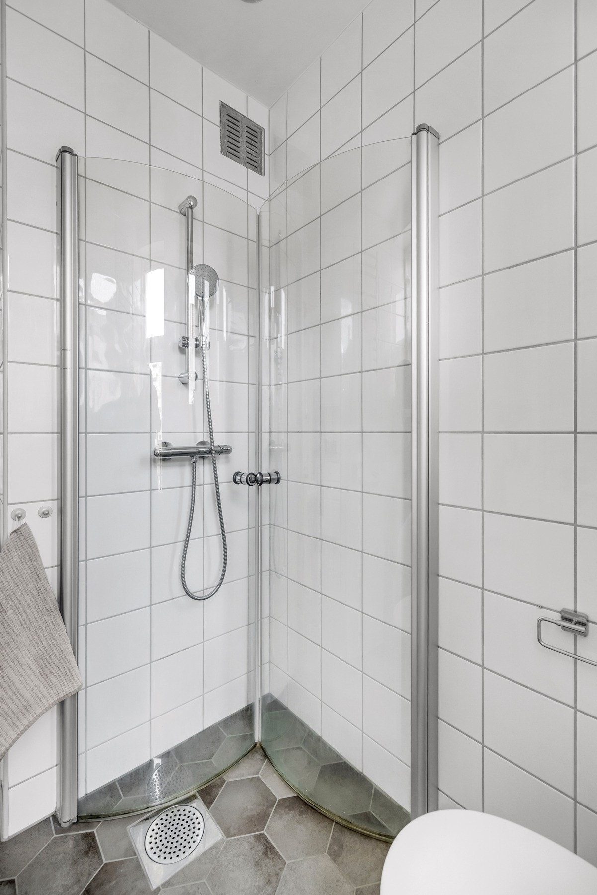 Badet er innredet med toalett, dusjhjørne med vegger og dører i herdet glass, servant og speil med overlys. Galleribilde