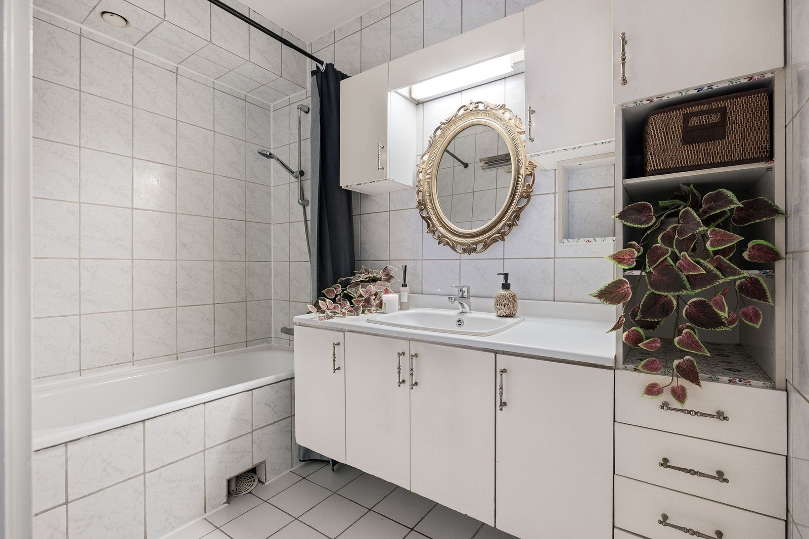 Flislagt baderom med badekar med dusj, stor innredning med god oppbavering og nedfelt servant. Galleribilde