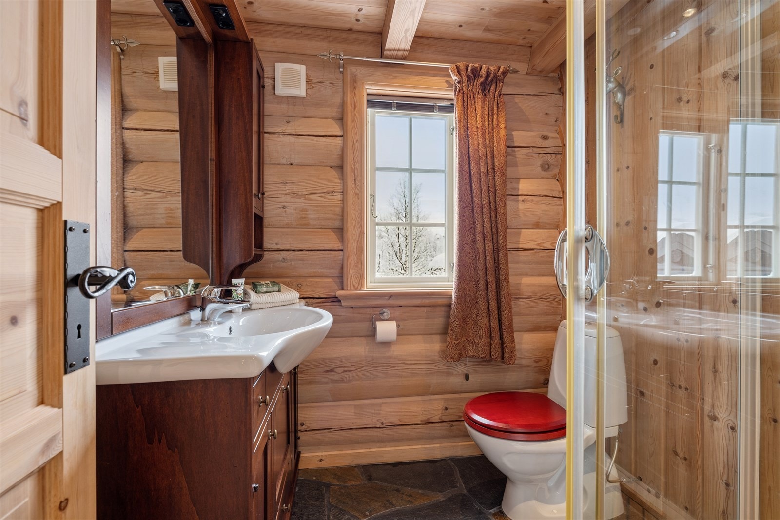 Ensuitebadet byr på skifer, treverk og en harmonisk atmosfære som passer hyttens gjennomførte stil. Galleribilde