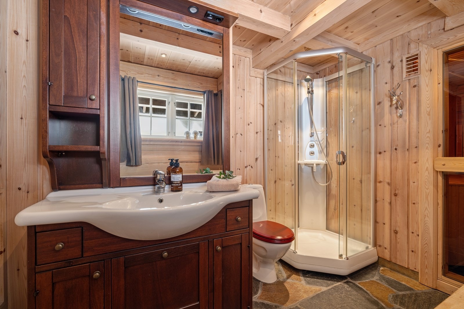 Bad- og vaskerommet er utført i naturmaterialer med skifer og treverk som skaper en rolig fjellfølelse. Galleribilde