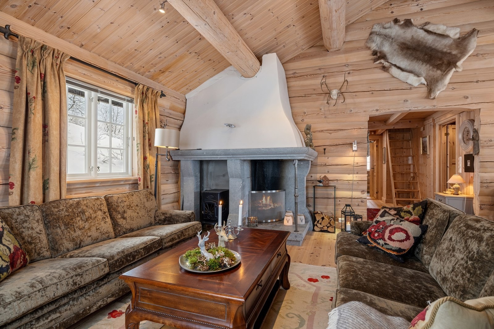 Hovedstuen åpner seg med vinduer i tre retninger og en flott åpen peis som rommets midtpunkt. Galleribilde