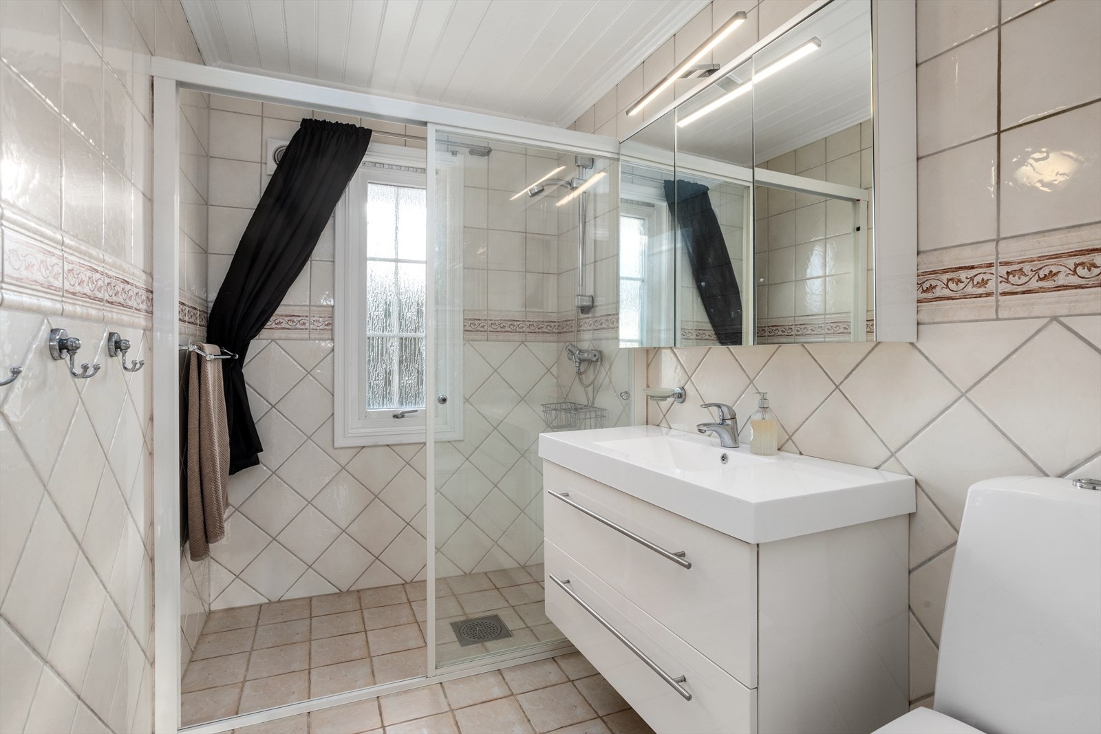 Baderommet er pusset opp på 1990-tallet. Baderomsinnredningen er utskiftet i nyere tid. Vinduet mot syd sørger for innslipp av naturlig lys. Innerst på badet er det en raus dusjsone med nisje av glidedører av herdet glass. Galleribilde