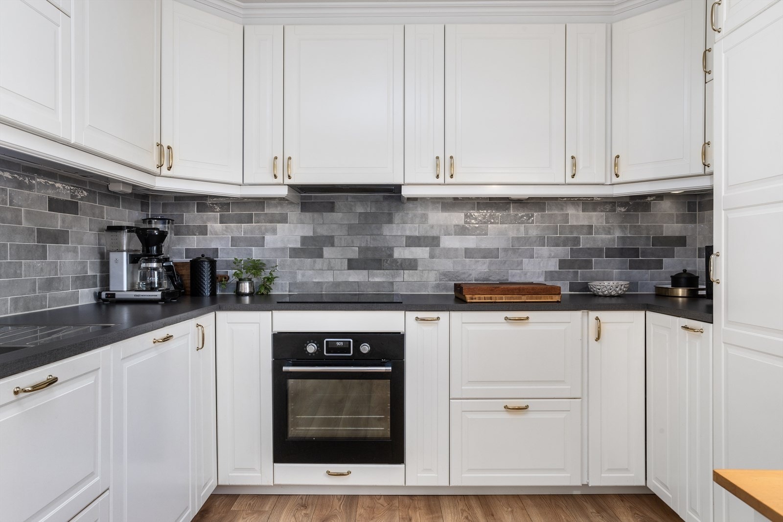 Innredning i hvit profil utførelse hvor det godt med skap- og benkeplass. Innredningen byr blandt annet på detaljer som noe bruk av praktiske kolonialskuffer, praktisk hjørnerondell, innslag av glassdører i høyskap og dempere på på skuffer og dørknekter. Galleribilde