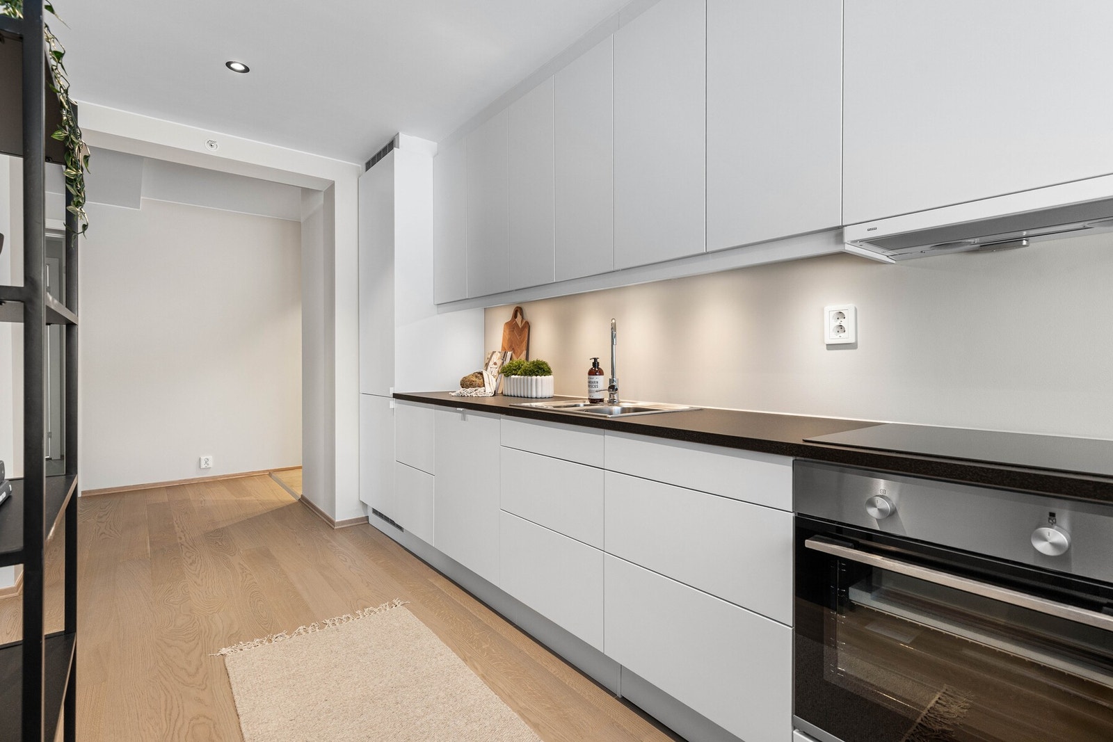 Gjennomført kjøkken med rene linjer og praktisk belysning under overskapene Galleribilde