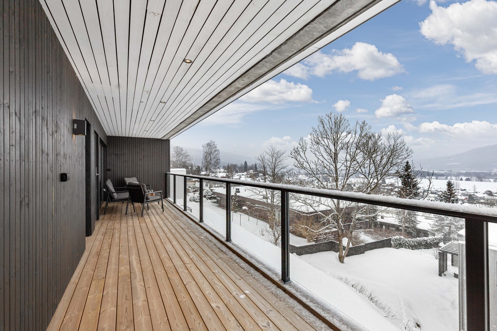 Balkongen har glassrrekkverk og spotter i taket, som gir et moderne preg over uteplassen Galleribilde