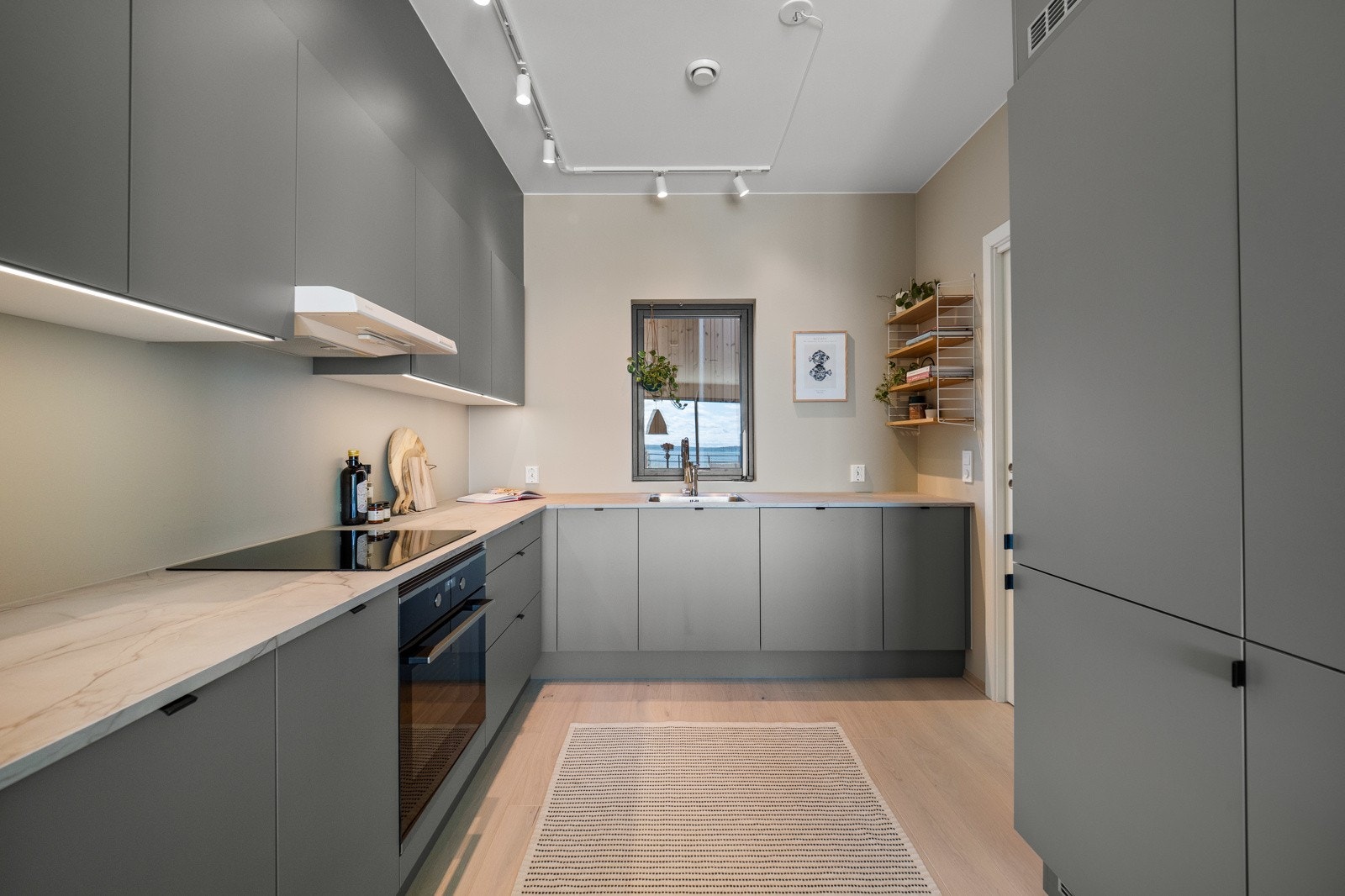 Lekkert kjøkken fra HTH med slette fronter og laminert benkeplate med nedfelt oppvaskkum. Integrerte hvitevarer. Galleribilde