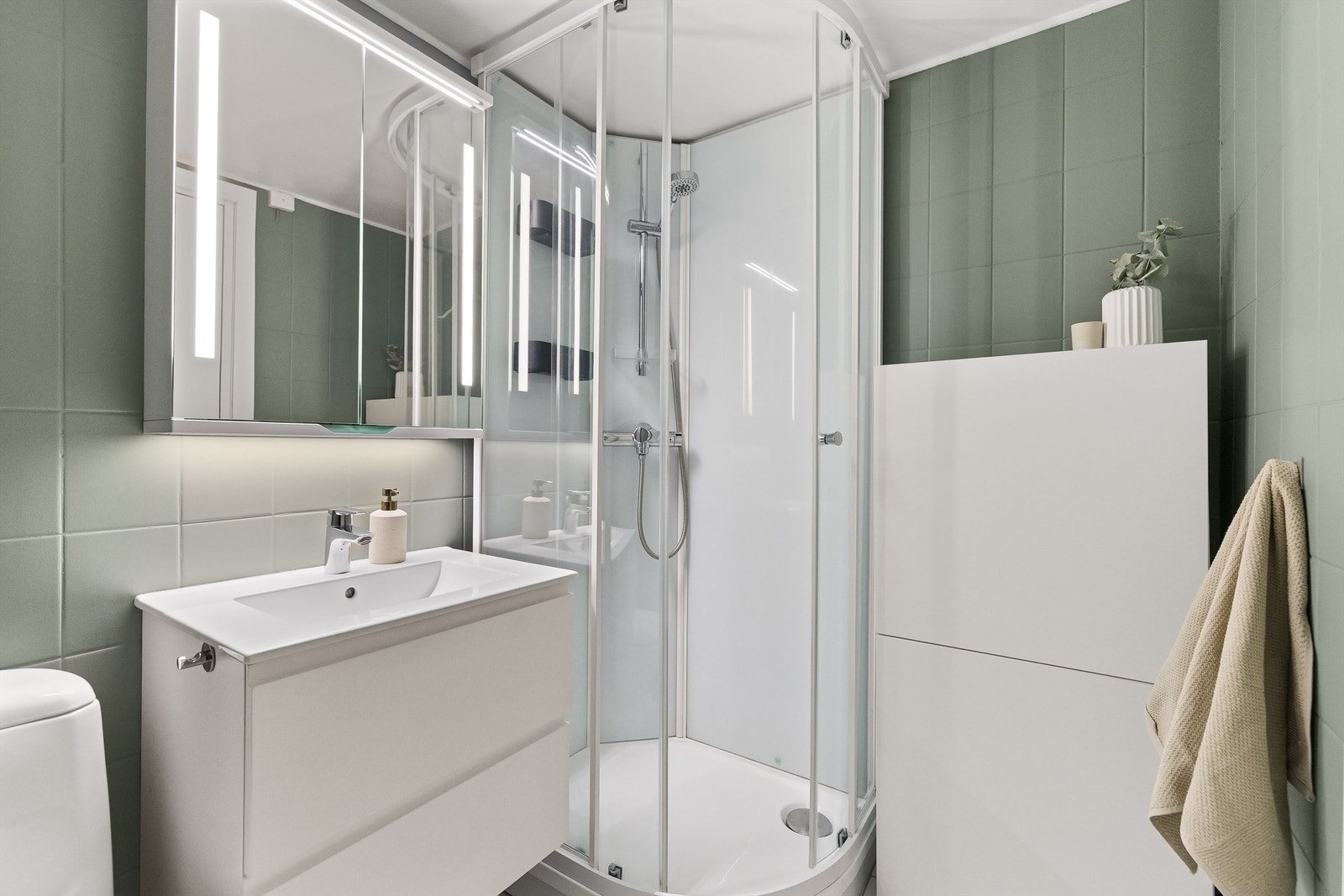 Badet er innredet med servantskap med ovenpåliggende servant med ett-greps armatur, over servant er det speilskap med belysning Galleribilde