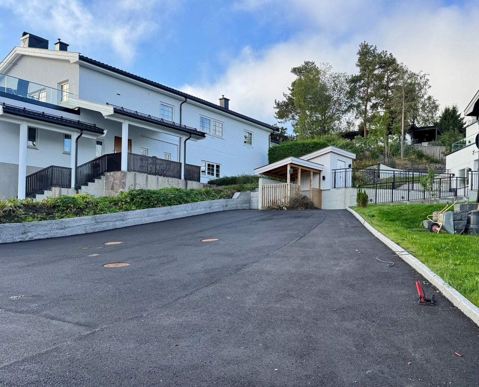 Sommerbildet viser stor asfaltert gårdsplass med god plass til mange biler | varmekabel i sti fra fortau og opp til huset | varmkabel i noen utvendige trapper Galleribilde