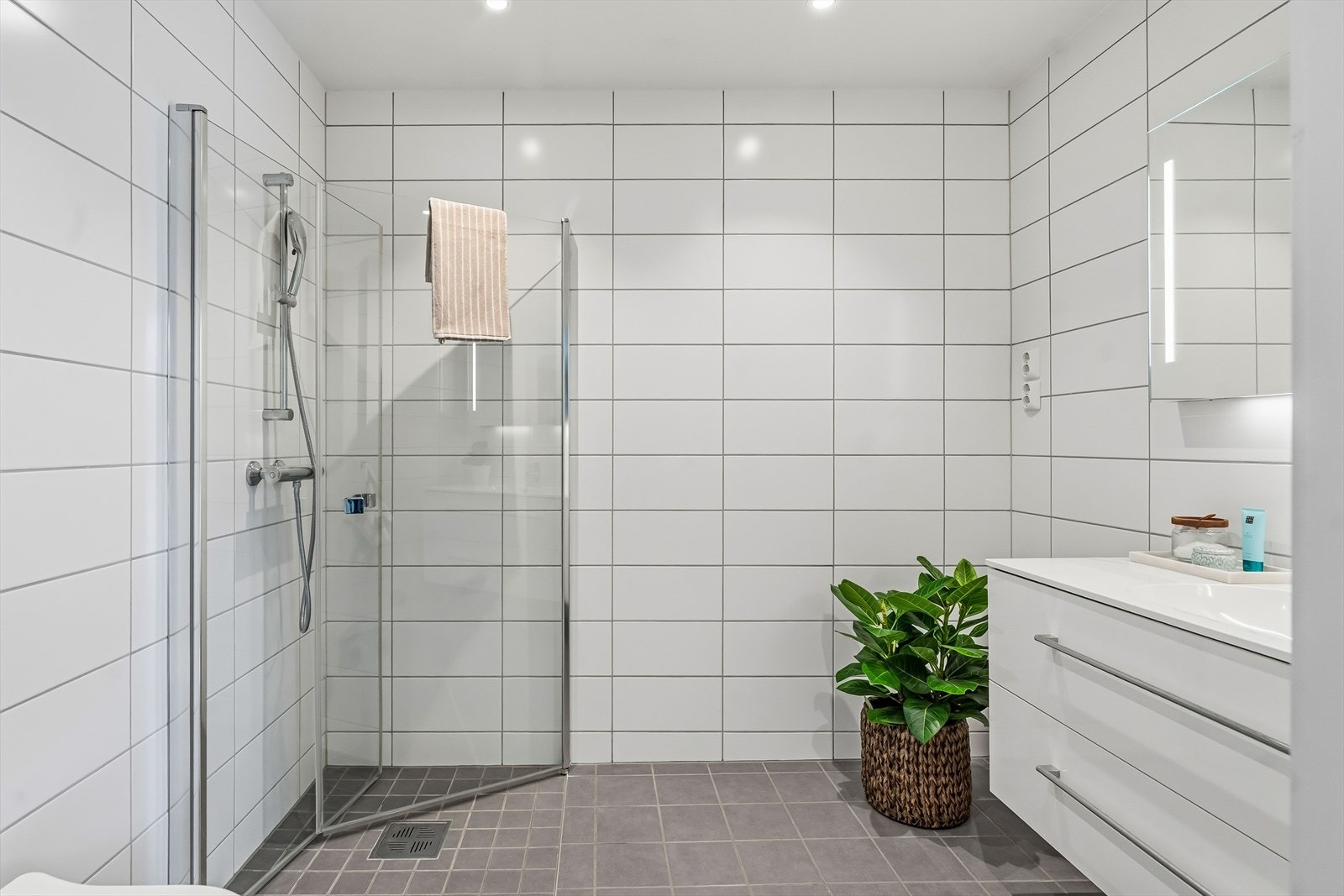 Boligen har hele tre bad. Dette har lyse veggfliser og grå gulvfliser. Galleribilde