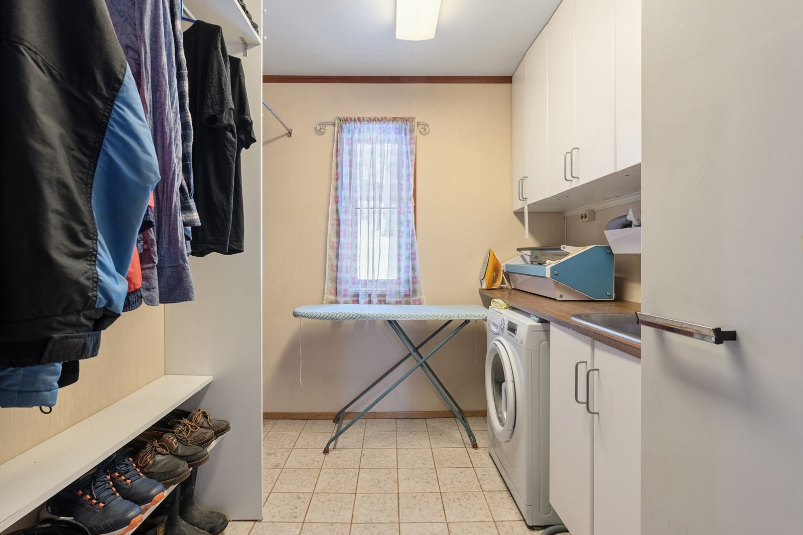 Praktisk separat vaskerom med opplegg for vaskemaskin, og som er videre innredet med skap, benkeplate og oppvaskkum i stål Galleribilde