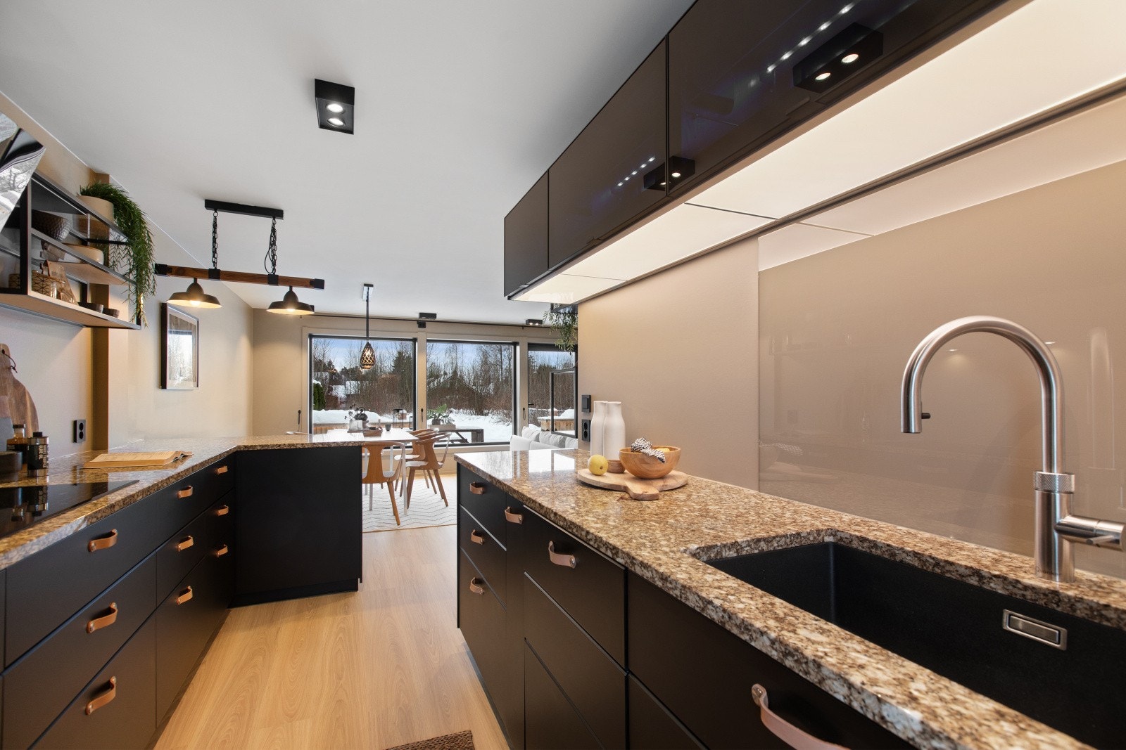 Stilren innredning fra 2019 med sorte, glatte fronter og granitt benkeplate med en underlimt kum og ett-greps blandebatteri. Galleribilde