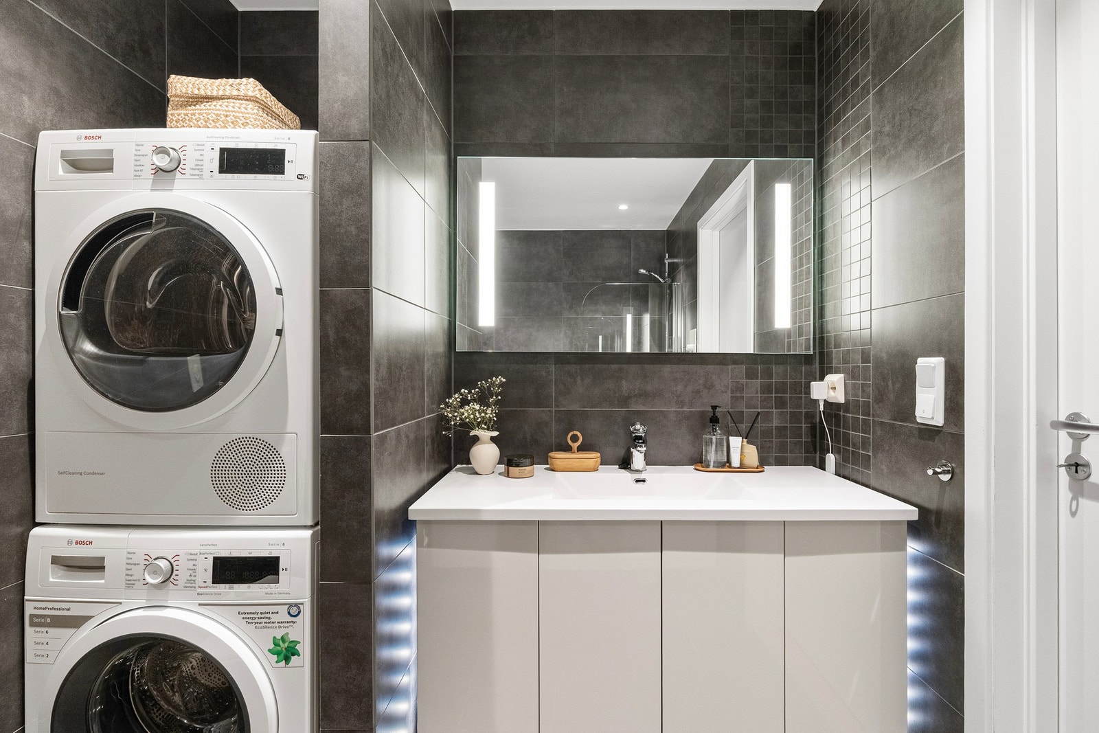 Badet er innredet med servant på skapseksjon, speil med belysning, vegghengt toalett, badekar samt opplegg for vaskemaskin. Galleribilde