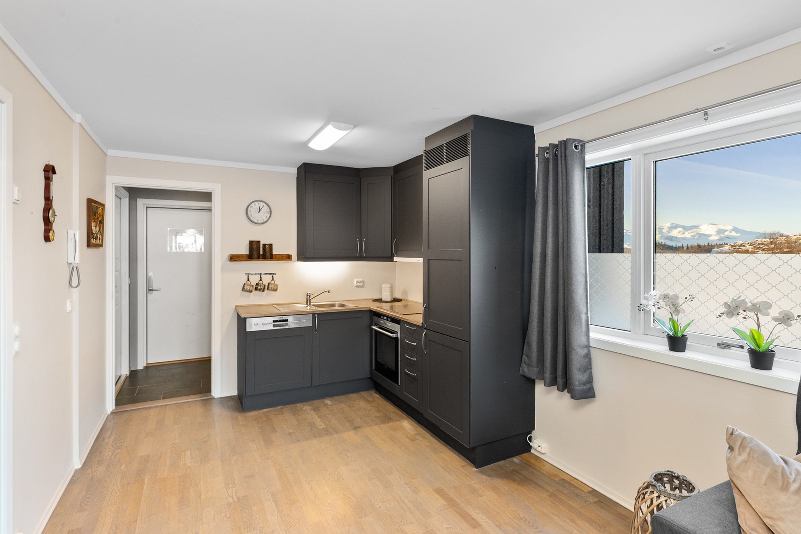 Gråmalt kjøkkeninnredning med profilerte fronter. Integrerte hvitevarer som oppvaskmaskin, stekeovn, platetopp og kjøl/frys Galleribilde