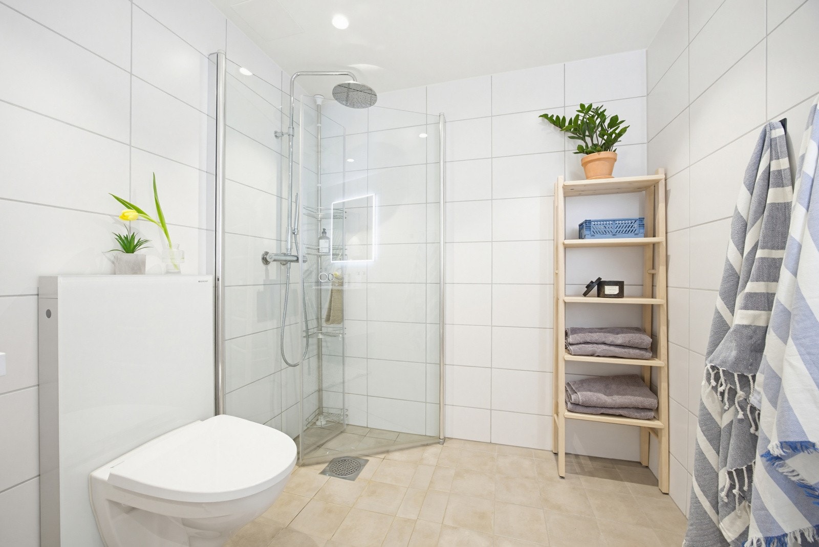 Badet har opplegg for vaskemaskin, stor servant med underskap, speil med belysning, downlights, vegghengt toalett og dusjdører i glass. Galleribilde