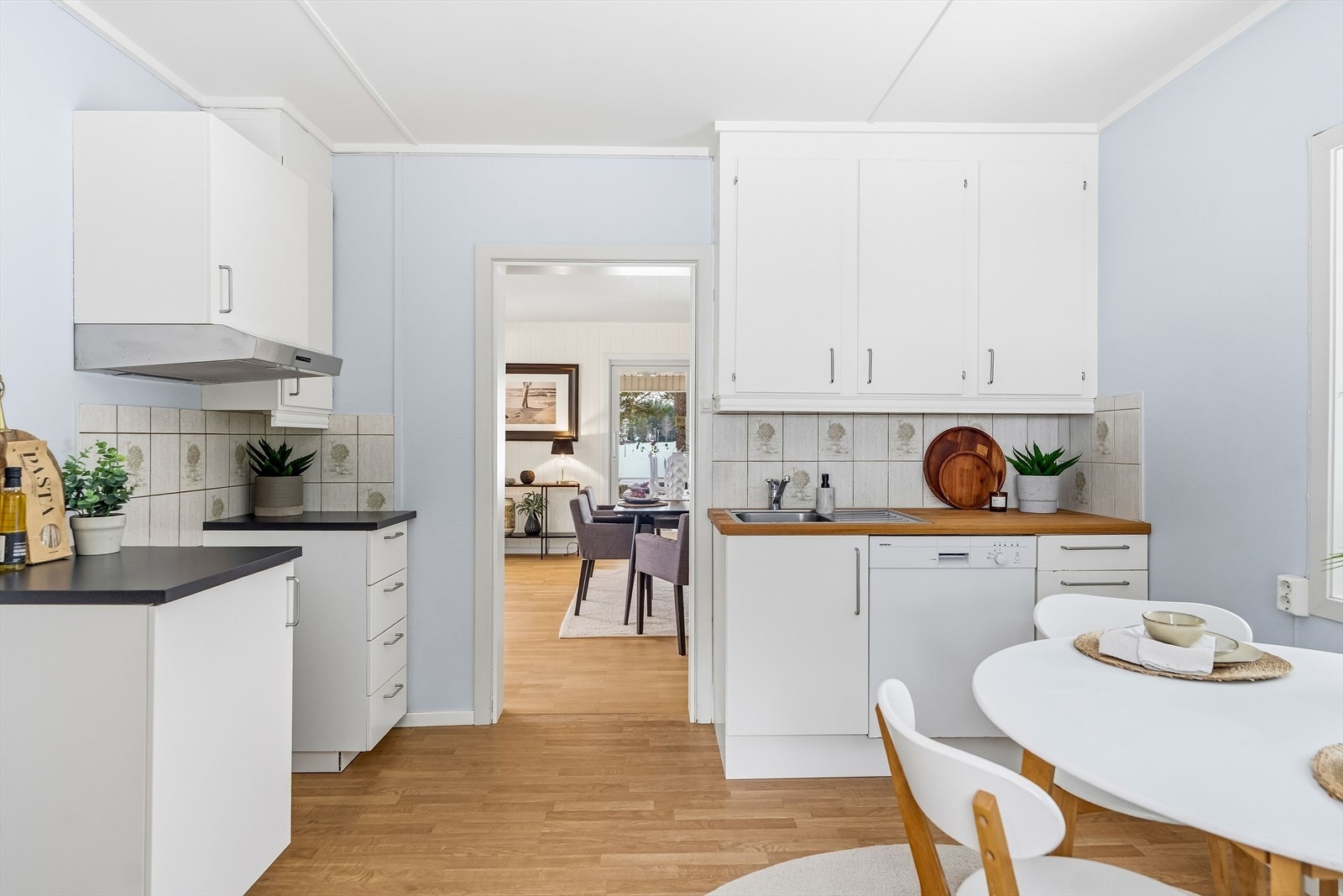 Innredningen har oppvaskmaskin, hendige høyskap, nedfelt oppvaskkum, benkeplate av laminat og hvite, glatte fronter malt i 2025. Galleribilde