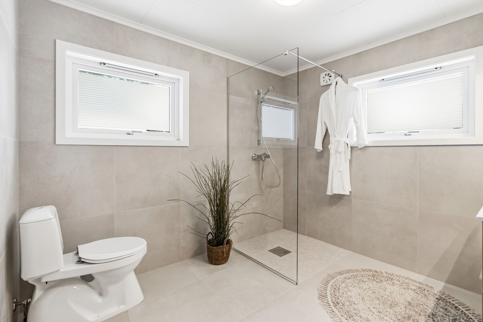 Badet er meget lekkert pusset opp i 2025, og har store, grå vegg- og gulvfliser med fint fargespill. Galleribilde