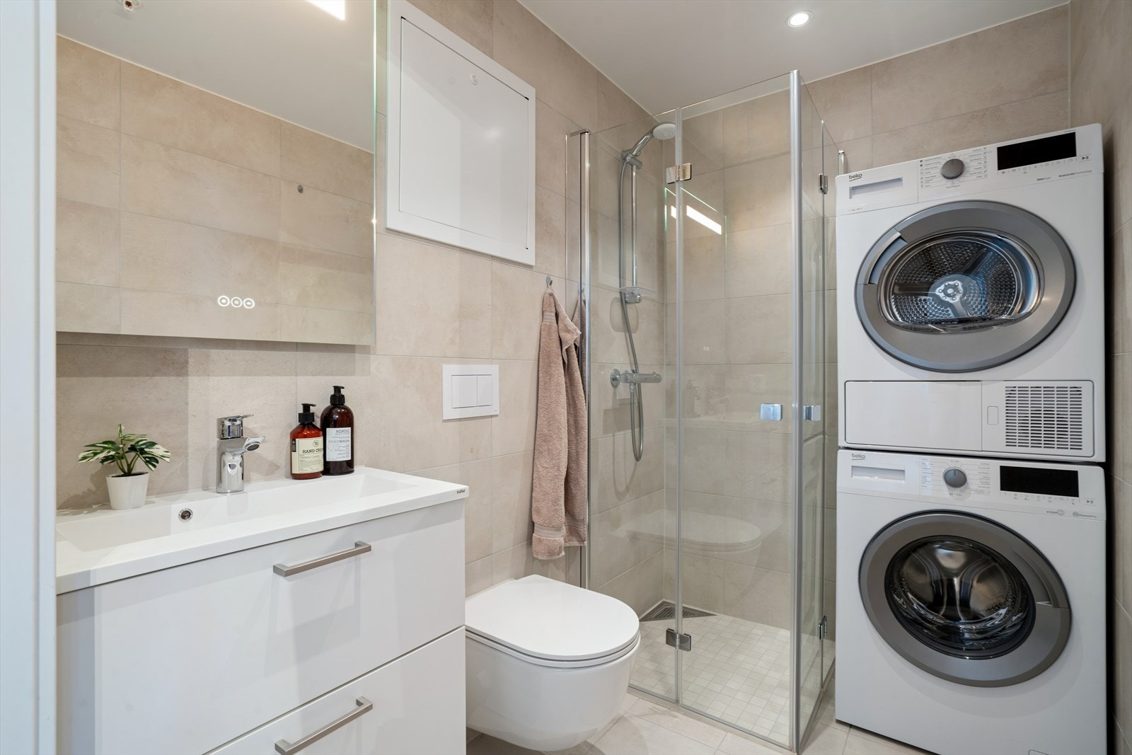 Badet har vannbåren gulvvarme og innfelte downlights for behagelig belysning. Det er opplegg for vaskemaskin og plass til tørketrommel. Galleribilde