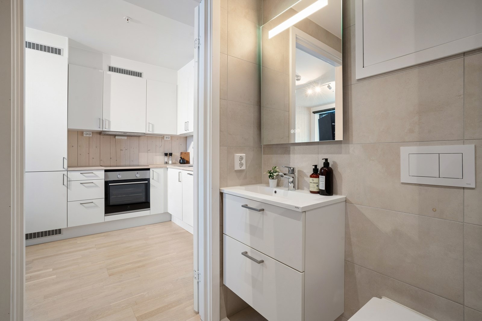 Badet er innredet med vegghengt toalett, dusjhjørne med glassdører og servant med tilhørende underskap. Galleribilde