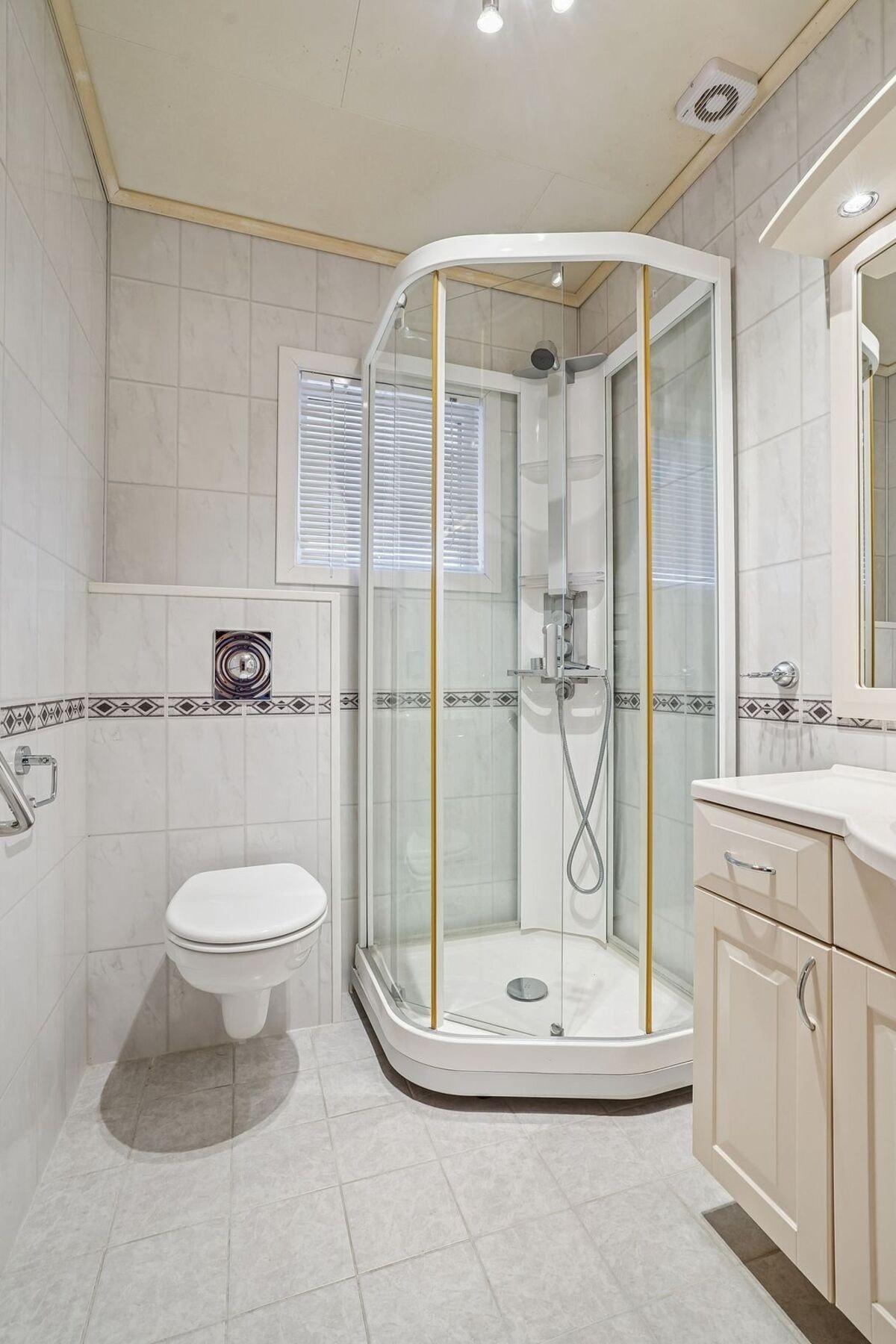 Badet er utstyrt med dusjkabinett, vegghengt toalett og innredning med servant. Galleribilde