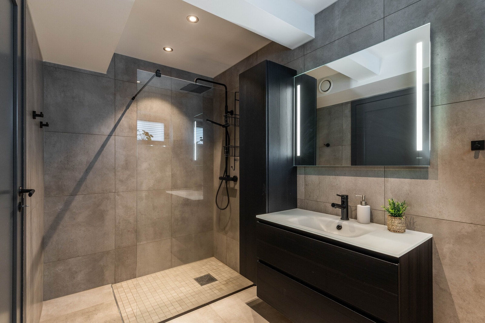 Stilrent baderom med store fliser, regndusj og tidsriktig baderomsinnredning Galleribilde