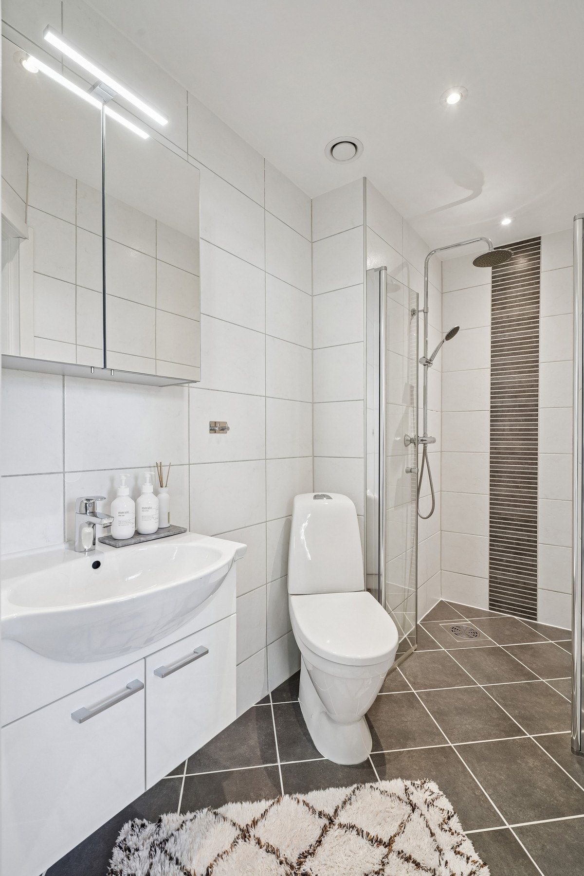 Badet er utstyrt med innrending, toalett og dusjhørne med glassdører og vegghengt dusjgarnityr med rainshower. Galleribilde