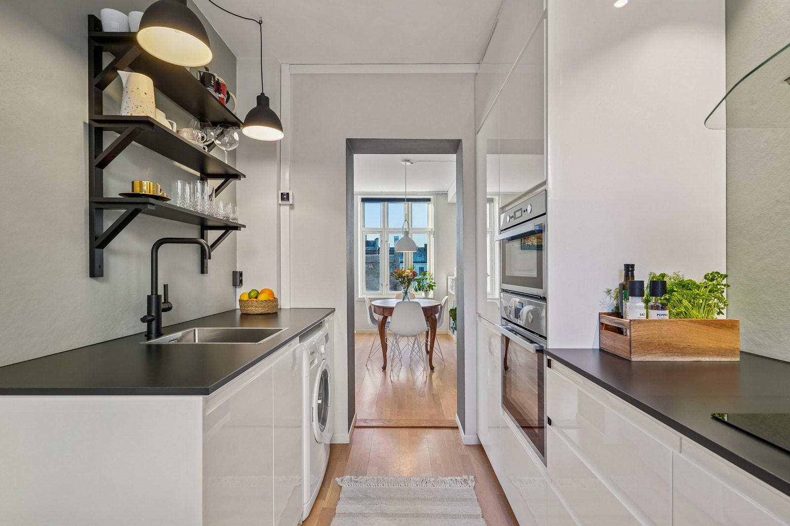 Pen kjøkkeninnredning med lyse høyglansfronter og laminat benkeplate. Galleribilde