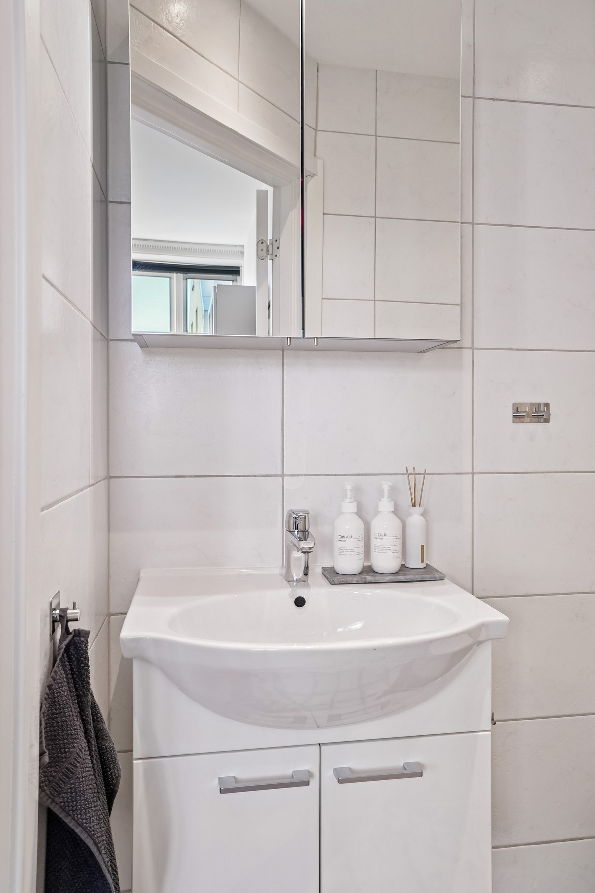 Baderomsinnredning med glatte skapfronter. Helstøpt servant og skapspeil med belysning over. Galleribilde