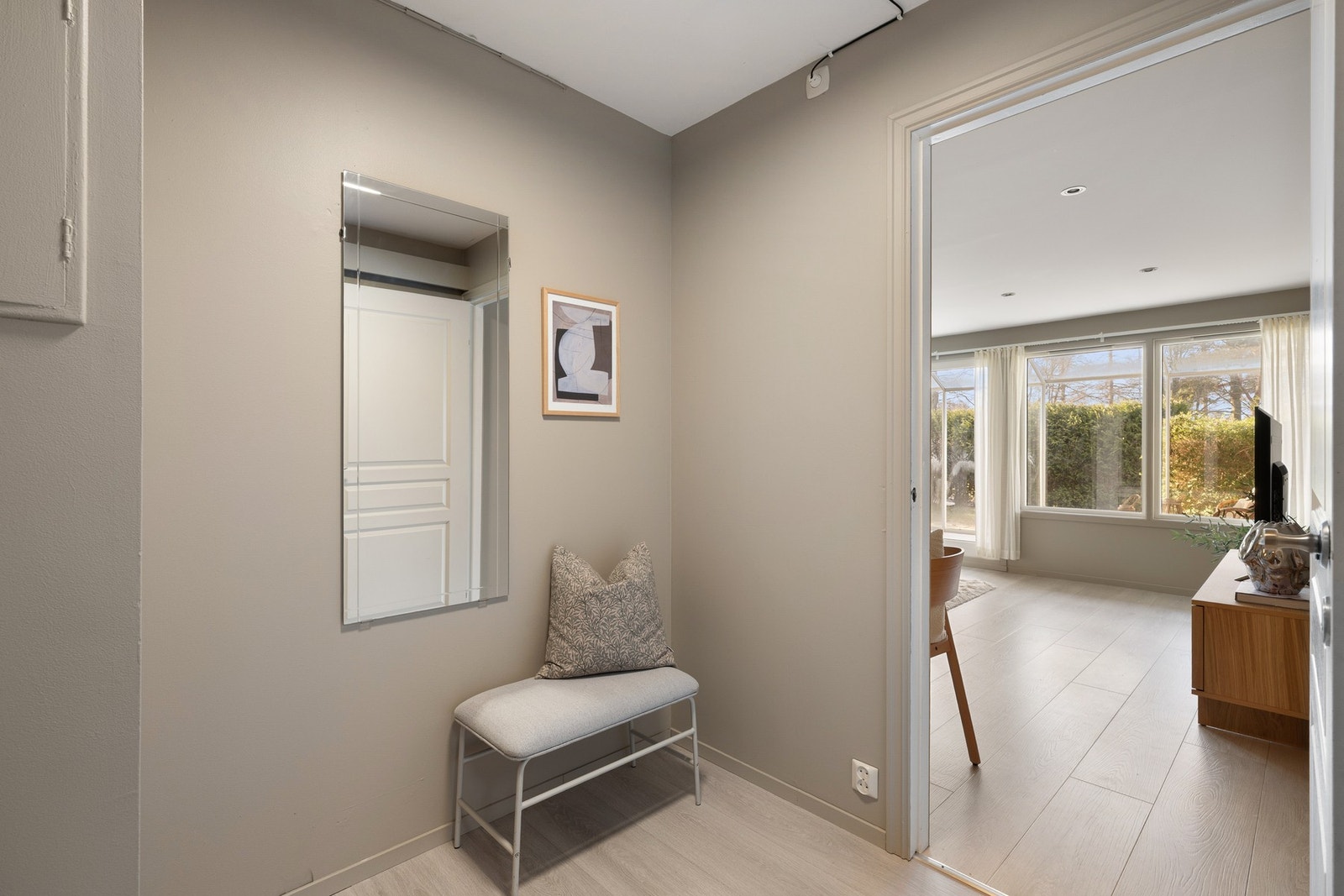 Leiligheten ligger i byggets første etasje med inngang til en pen entré som har laminatgulv fra 2026 og veggflater i en dus, harmonisk fargetone. Galleribilde