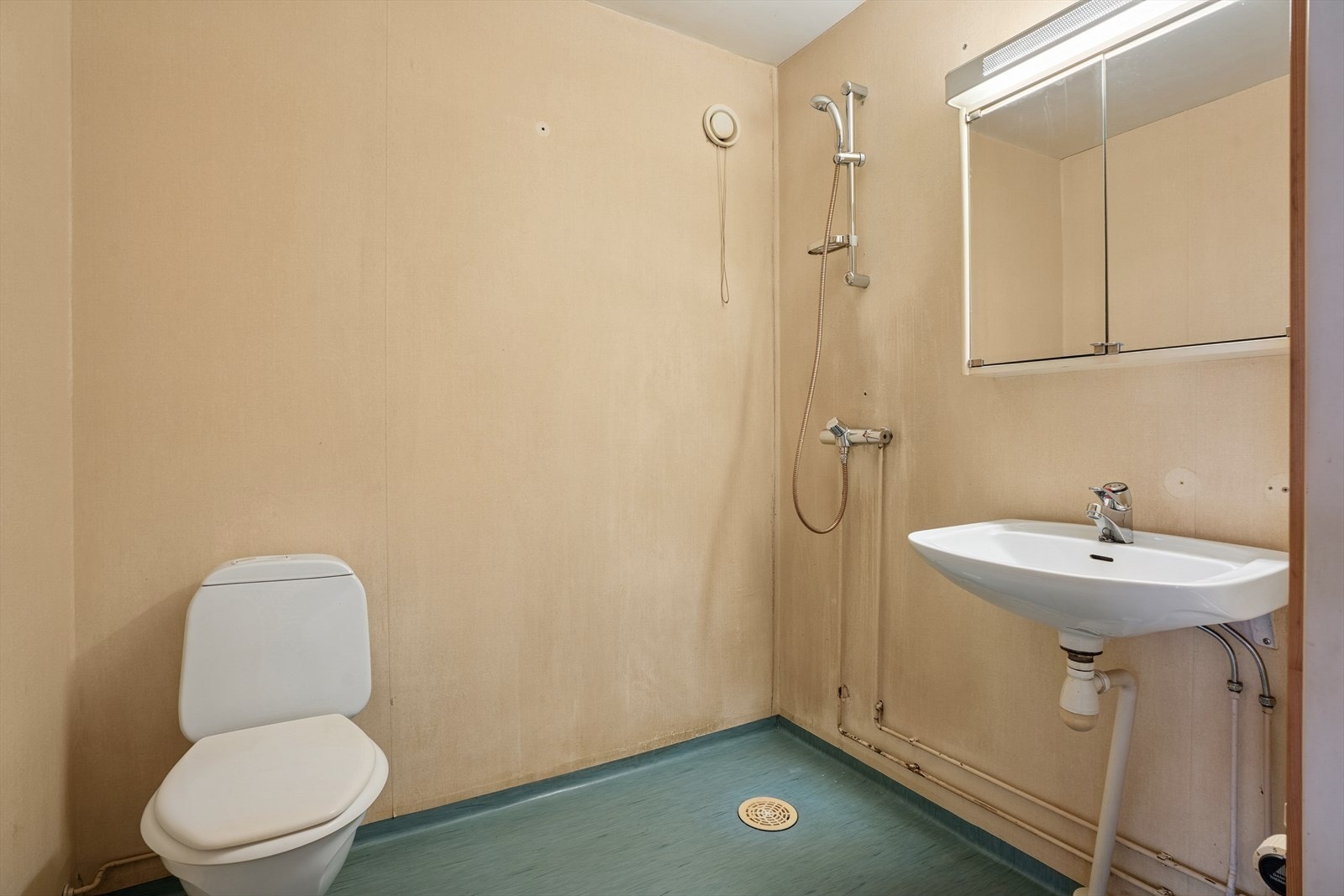 Baderommet oppe er innredet med servant og speilskap med lysarmatur montert på vegg, gulvmontert toalett og dusjhjørne med dusjutstyr. Galleribilde