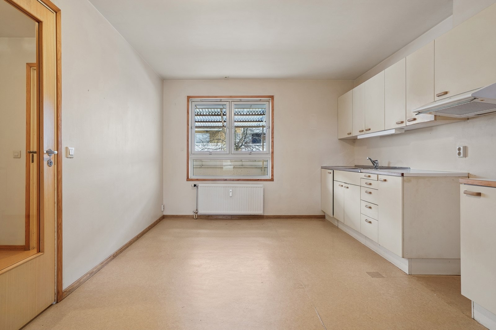 Kjøkkeninnredning med glatte, folierte fronter, laminat benkeplate med heldekkende benkebeslag i rustfritt stål og lysstoffrør under overskap. Galleribilde