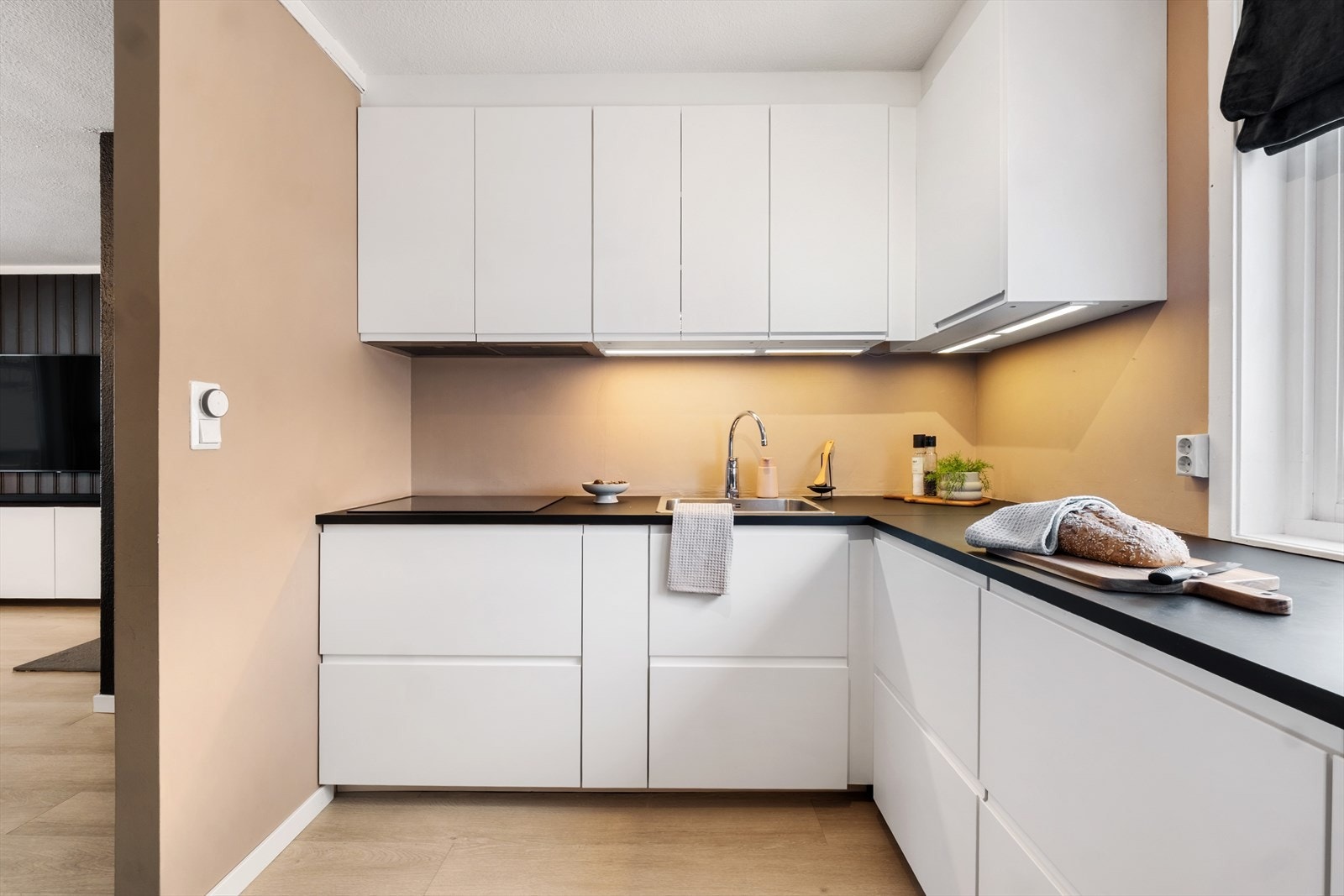 Hvite fronter med integrerte håndtak og sort laminat benkeplate. Galleribilde