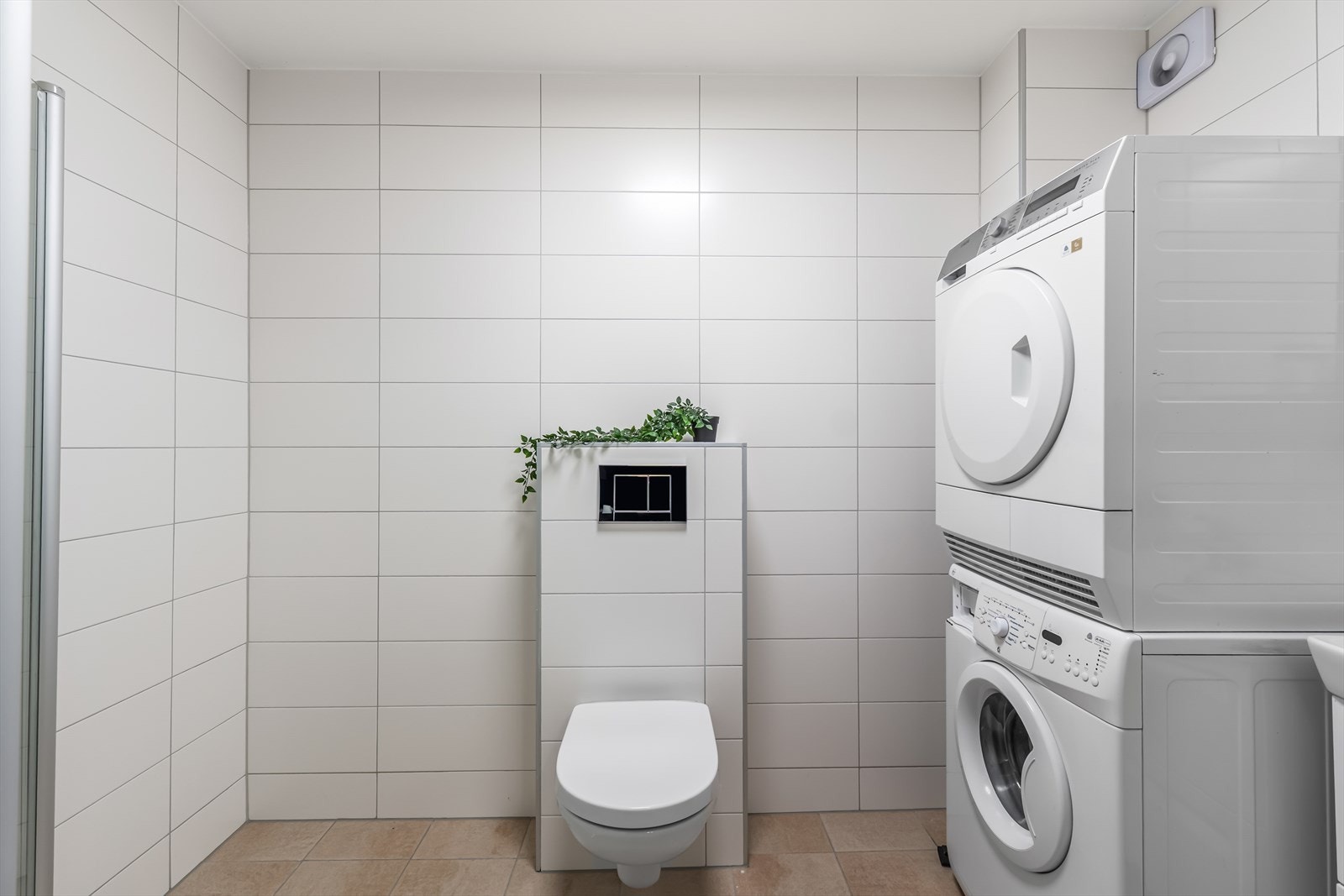 Badet er innredet med servantinnredning, speilskap og veggmontert toalett med innebygget sisterne. Galleribilde