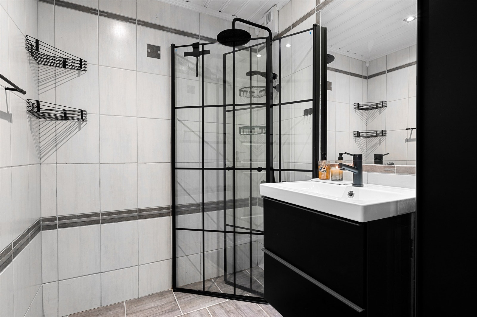 Pent flislagt bad på 3 kvm med gulvvarme og downlights. Videre er badet innredet med servantskap med speil og dusjhjørne med regndusj. Galleribilde