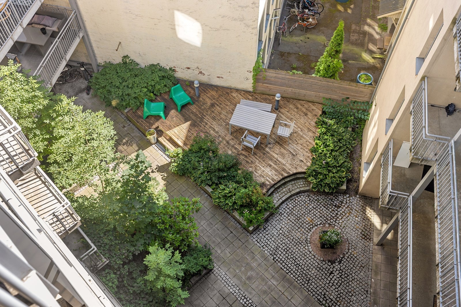 Oversikt over gårdsrommet viser sittegrupper og frodig vegetasjon. Galleribilde