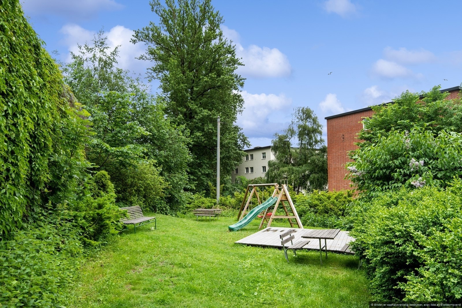 Fellesarealet er pent opparbeidet med hellestein, bed, trær, variert beplantning, sittegrupper, sykkelskur og asfalterte gang- og stikkveier. Galleribilde