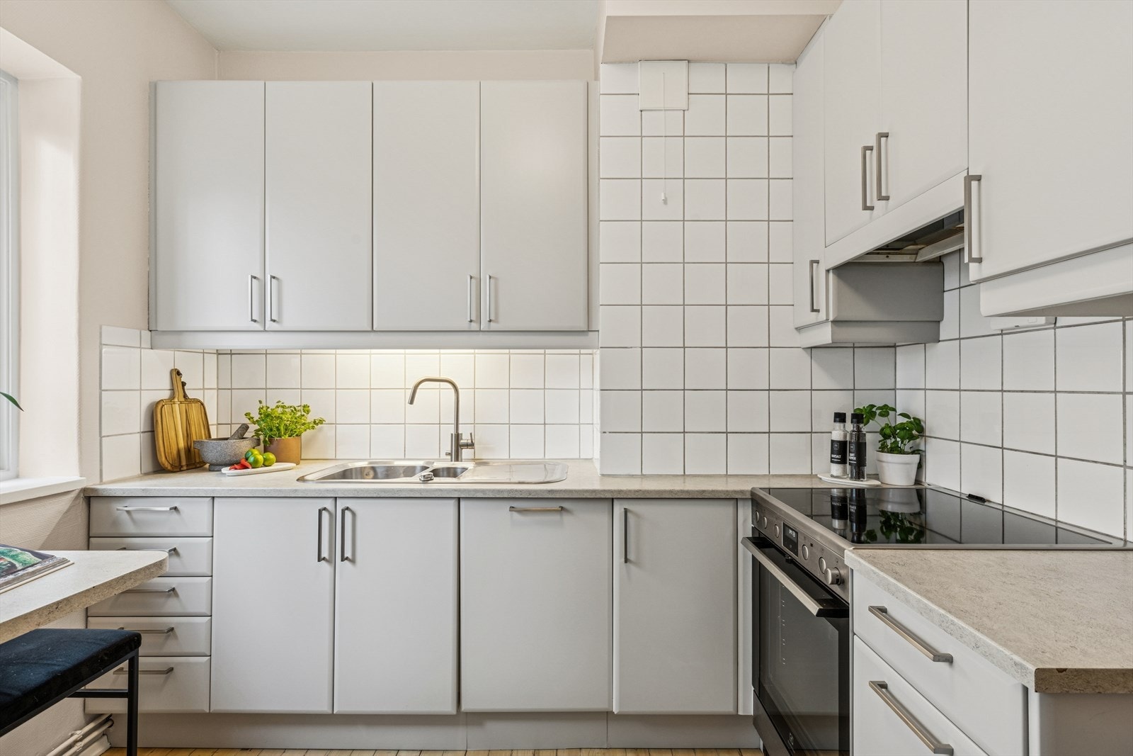 Den robuste laminatbenkeplaten med nedfelt stålkum, kombinert med fliser mellom benk og overskap, gir en tidløs og elegant stil. Galleribilde