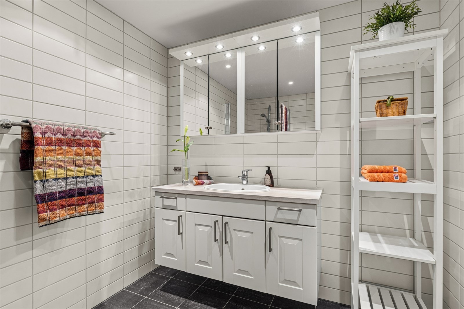 Flislagt bad med romslig servantinnredning og speilskap med belysning. Galleribilde